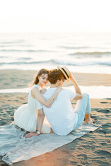 Fototapeta na wymiar Woman hugging man shoulder while sitting on the beach