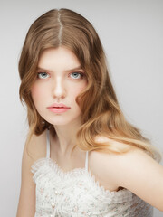 One young woman looking at camera. Vertical studio portrait of young charming girl.