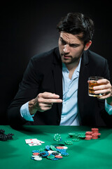 Emotional Handsome Caucasian Brunet  Pocker Player At Pocker Table With Chips and Cards While Playing and Drinking Alcohol
