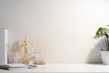 Comfortable workplace with potted plant, glass of water and notebook on white table. Copy space for your advertise text.