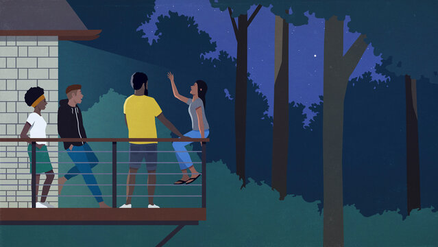 Friends talking on balcony in woods at night
