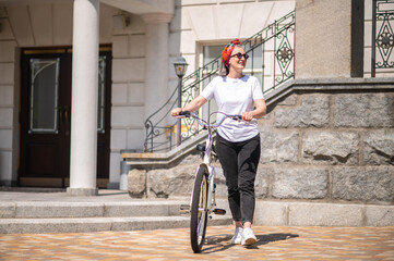 Good-looking mature woman with a bike on a summer day