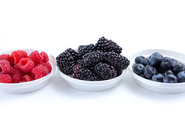 A view of a variety of berries in bowls, against a white background.