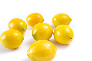 A view of several Meyer lemons, against a white background.