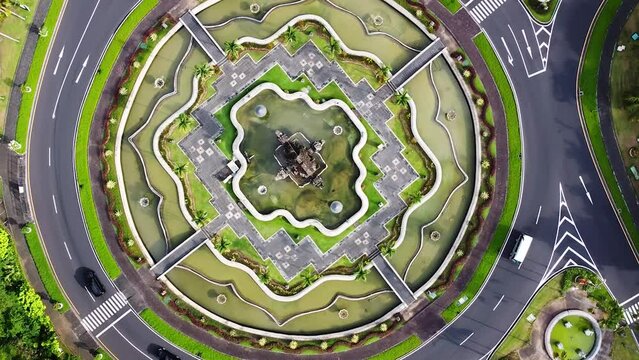 Rotating birdseye Drone shot of traffic moving around a beautiful roundabout in Indonesia