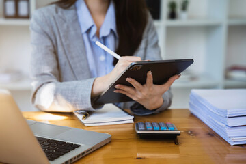 Female businessman working with tablet and calculator, business document and laptop computer notebook.