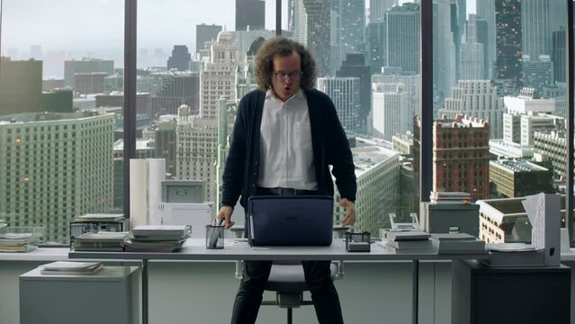 CRASH ZOOM OUT Portrait of angry nerdy office worker loosing control and sweeping all his stuff off the table in rage