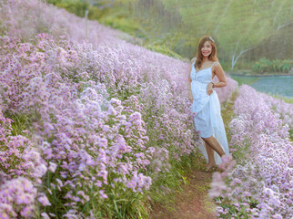 Fototapeta na wymiar Young beautiful woman wearing white dress relaxing in aromatic flowers field.