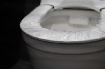 disposable cover pad on the rim of the toilet seat. wc hygiene system in public washroom. toilet...