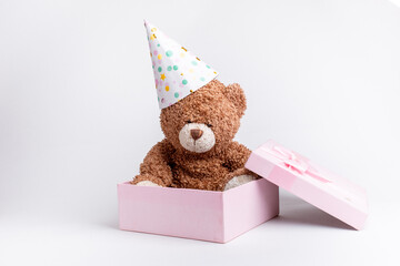 a teddy bear in a pink gift box celebrates a birthday on a white background, isolated
