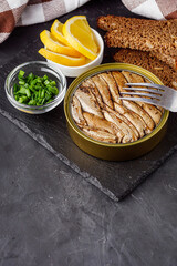 canned sprats in oil on a dark stone background