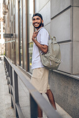 A handsome smiling man with a backpack in the city street