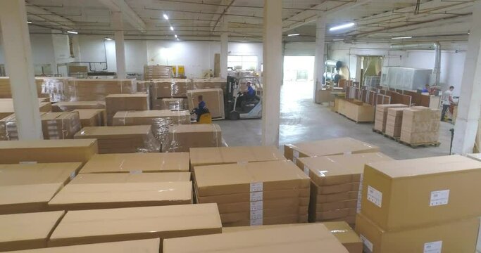 Warehouse with boxes in a factory. Large warehouse with finished products in the factory. A forklift in a large warehouse moves boxes