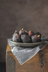 Black fresh figs in a metalic plate on dark background. Copy space