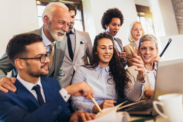 Group of young confident business people analyzing data using computer while spending time in the office