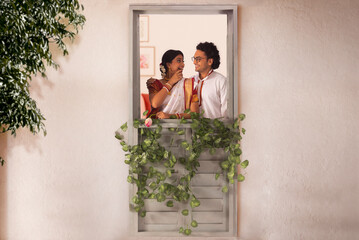 Happy Bengali couple standing together by window