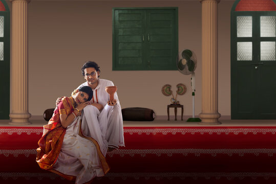 Bengali couple sitting on the steps of courtyard on the occasion of Durga  Puja