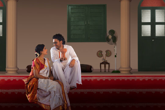 Bengali couple sitting on the steps of courtyard and talking on the occasion of Durga  Puja