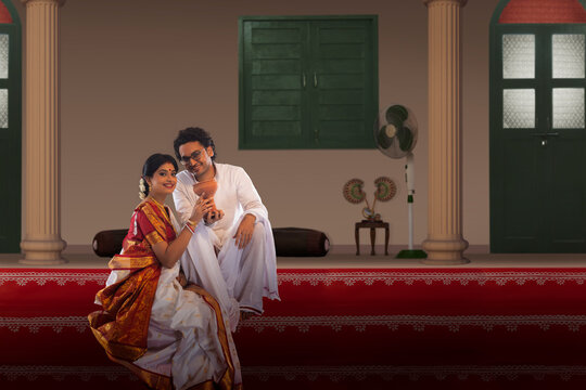 Bengali couple sitting with dhunuchi on the steps of courtyard on the occasion of Durga  Puja