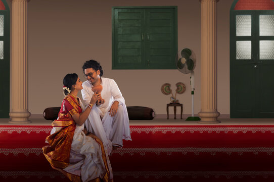 Bengali couple sitting with dhunuchi on the steps of courtyard on the occasion of Durga  Puja