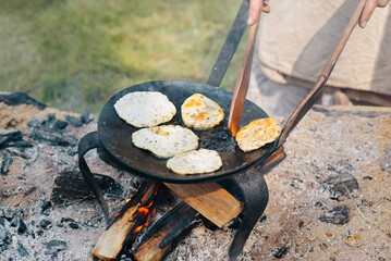 Close-up cooking cereal pancakes on campfire according to an old traditional recipe outdoors....