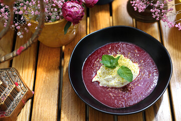 Dessert with forest fruit mousse, with pistachio powder topping, top view. Bowl with tasty dessert on a wooden table.