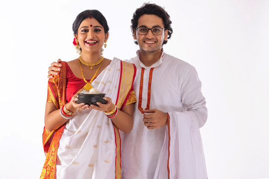 Portrait of happy Bengali couple standing together with rosogolla handi