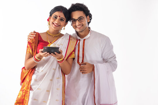 Portrait of happy Bengali couple standing together with rosogolla handi