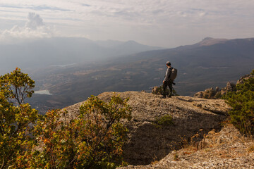 Fototapeta premium A tourist stands on the rock of the Demerdzhi mountain range with a view of the valley