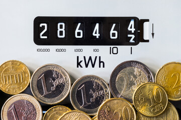 Close-up of electric meter and Euro coins. Focus on kWh symbol. Concept for global energy crisis, cost of living, high electricity prices, power, heating and higher bills. - obrazy, fototapety, plakaty