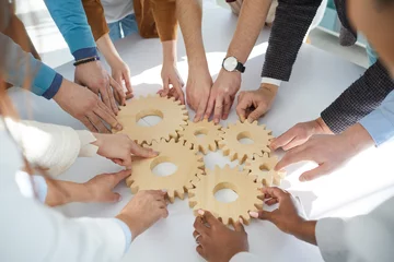 Foto op Plexiglas Close up of wooden gears that business people connect together during teambuilding session. Male and female colleagues together find business solutions and contribute to development of business. © Studio Romantic