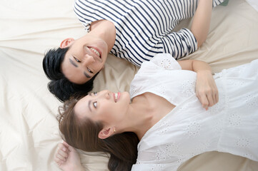 Top view of young asian couple on the bed in bedroom, happy family concept