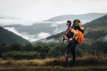 Fototapeta na wymiar Woman hiking with backpack and trekking poles on summer day. Nature tourism in Ukrainian Carpathian mountains.