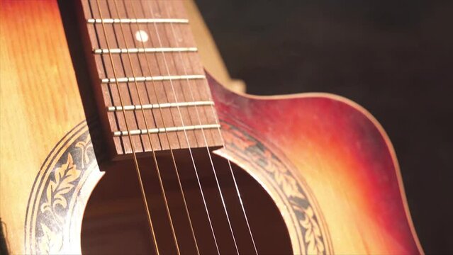 acoustic guitar body close-up, strings, bridge, resonator hole. smoky room. neck of an acoustic guitar. the rays of the sun are reflected on the guitar.