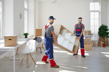 Fototapeta premium Male movers in uniform carry furniture help client with office or home settle. Deliverymen or carriers work for customer during moving or relocation. Delivery or transportation company service.