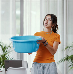 Woman collecting water leaking from the ceiling