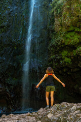 A young woman at the impressive waterfall at the Levada do Caldeirao Verde, Queimadas, Madeira