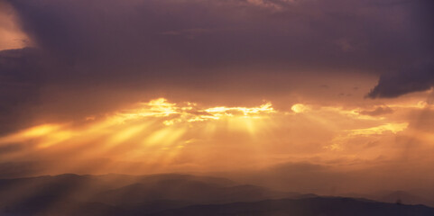 Fototapeta na wymiar Beautiful summer mountain landscape, clouds and sun rays at bright yellow sunset