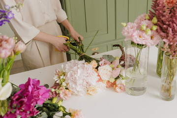 beautiful girl collects a bouquet of flowers in a flower shop