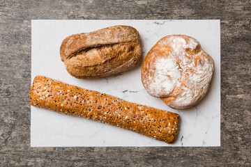 Assortment of freshly baked bread with napkin on rustic table top view. Healthy unleavened bread. French bread
