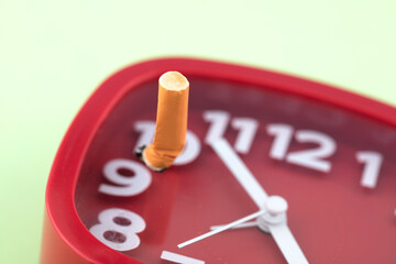 Cigarette butt on alarm clock quit smoking time