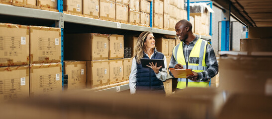 Two happy warehouse workers recording inventory