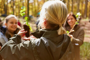 Female teacher and volunteers with tree seedlings in forest