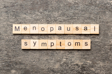 menopausal symptoms word written on wood block. menopausal symptoms text on cement table for your...