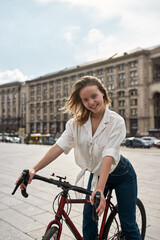 Caucasian girl posing with bicycle on city square