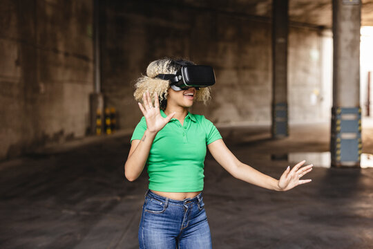 Smiling woman wearing virtual reality simulator gesturing in parking garage