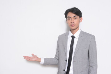 young businessman wearing gray suit, white shirt ,black, tie with welcome gesture standing in studio