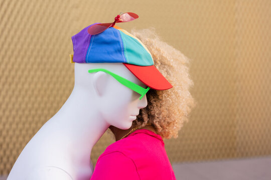 Young woman hugging woman wearing multi colored cap in front of wall
