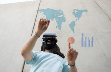 Smiling bearded man wearing VR glasses touching maps and chart