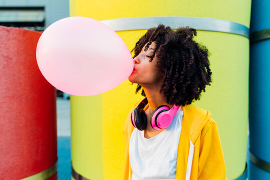 Young woman with eyes closed blowing bubble gum